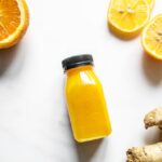 Assortiment coloré d'aliments anti-inflammatoires comprenant des baies, de l'ail, du curcuma, des agrumes, des légumes verts, des noix et du poisson gras, disposés sur une table en bois.