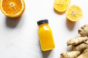 Assortiment coloré d'aliments anti-inflammatoires comprenant des baies, de l'ail, du curcuma, des agrumes, des légumes verts, des noix et du poisson gras, disposés sur une table en bois.