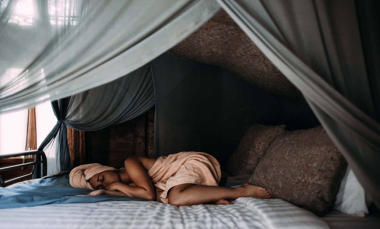 Image d'une femme paisible dormant dans une chambre sombre et calme, symbolisant les bienfaits du sommeil réparateur sur l'énergie quotidienne.